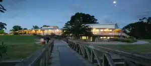Riverside Golf & Sports Centre clubhouse at dusk, viewed from the boardwalk across the course